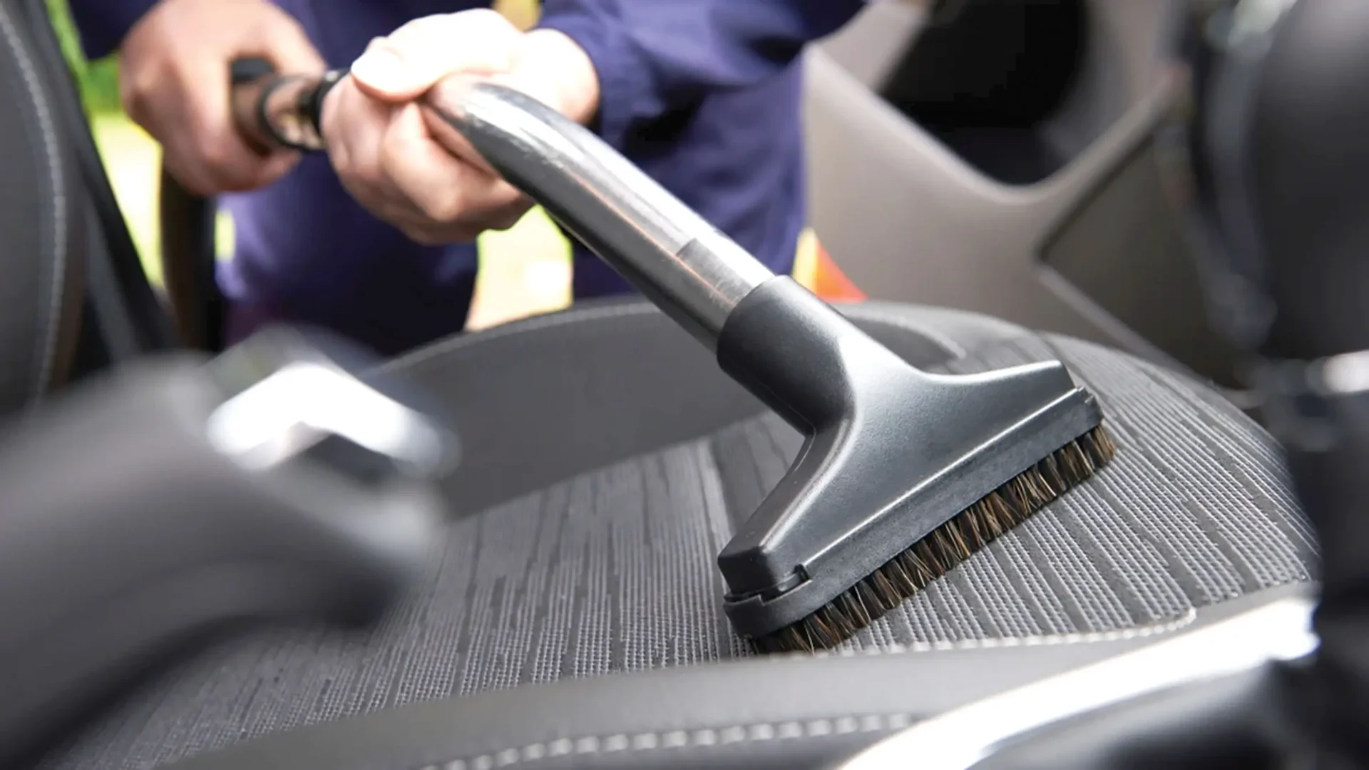 Profissional aspirando o interior de um carro durante processo de higienização automotiva